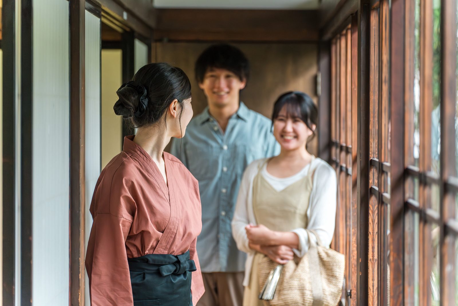 旅館の廊下で、到着した宿泊客を案内している仲居。